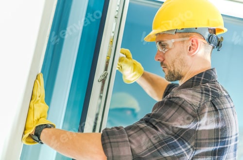 Construction Worker Installing Window Frame on New Building
