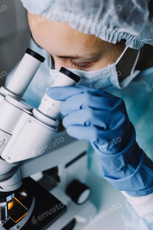Preview: Young scientist in uniform looking at microscope