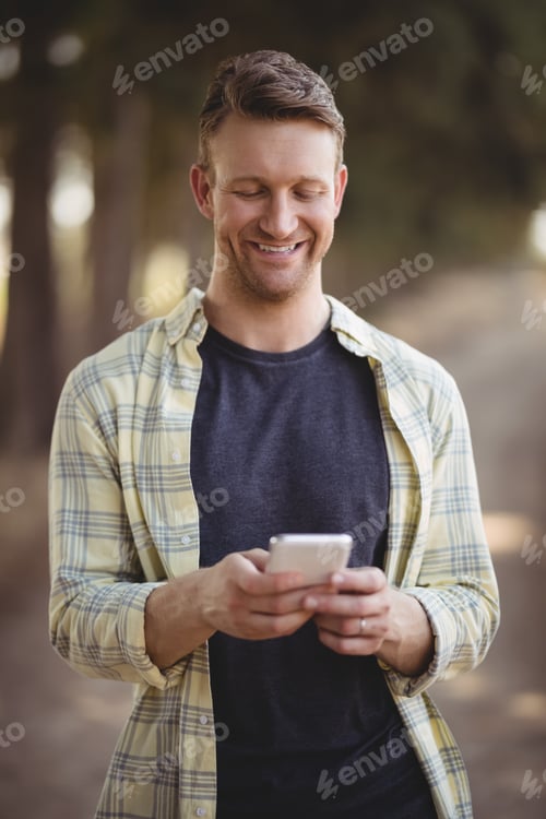 Preview: Smiling man using mobile phone at olive farm