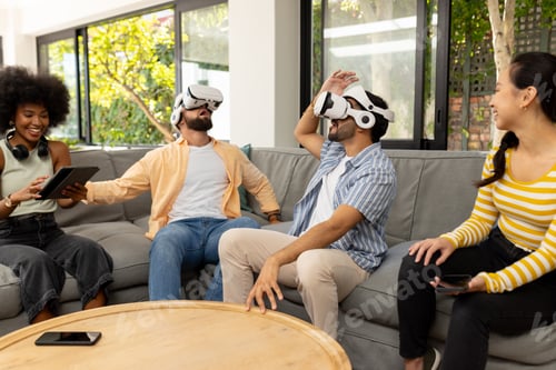 Preview: Using VR headsets, young diverse friends enjoying virtual reality gaming together