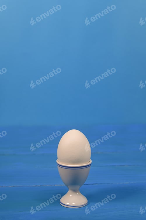 Preview: an egg in an egg cup. on a blue background.