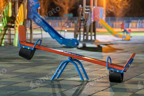 Preview: Seesaw swing in preschool yard with soft rubber flooring at night.