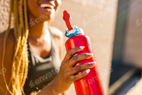 Preview: african american woman drinking smoothies after jogging in the downtown streets