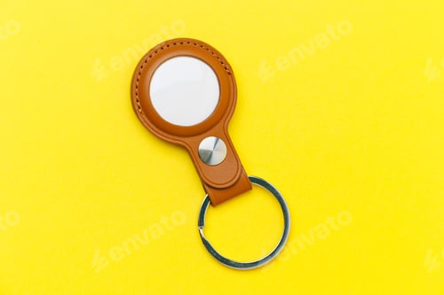 Preview: Closeup top view of a brown leather case with white Bluetooth tracker on the yellow background