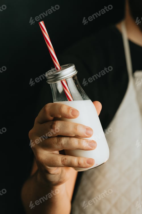Preview: Waiter holding a milkshake close up of the bottle with copy space and moody tones