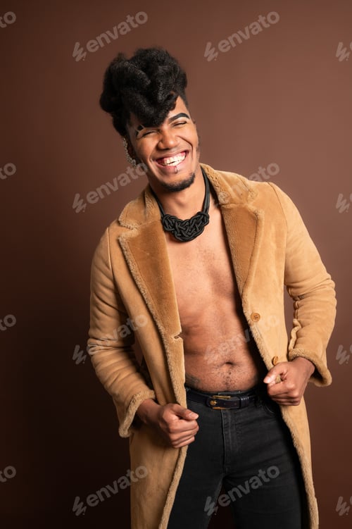 Preview: Stylish model smiling and opening fur coat on brown background