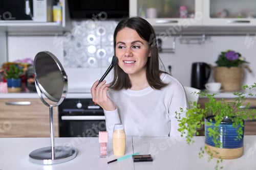 Preview: Young attractive woman doing makeup, female sitting at home