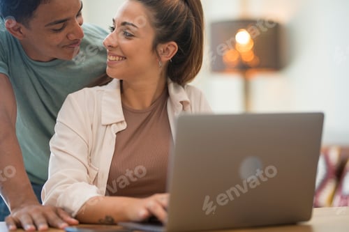 Preview: Young interracial couple working together with laptop. People lifestyle at home together