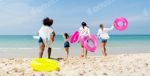Preview: Back of group of teenage girls hold swimming ring and ball also run to the sea and they look happy