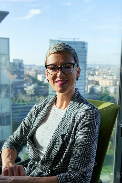 Preview: Portrait of a caucasian businesswoman smiling in modern office with city views.