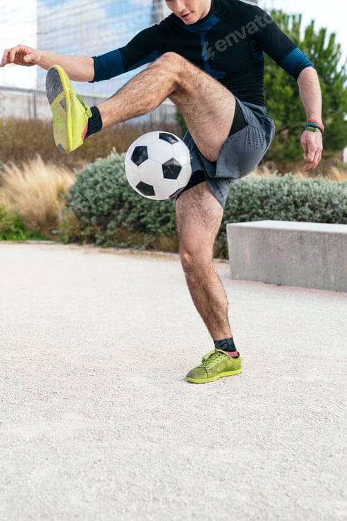 Preview: Young man juggling soccer ball in urban park