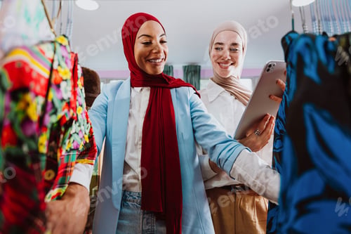 Preview: Modern diverse muslim women shopping clothing on digital tablet