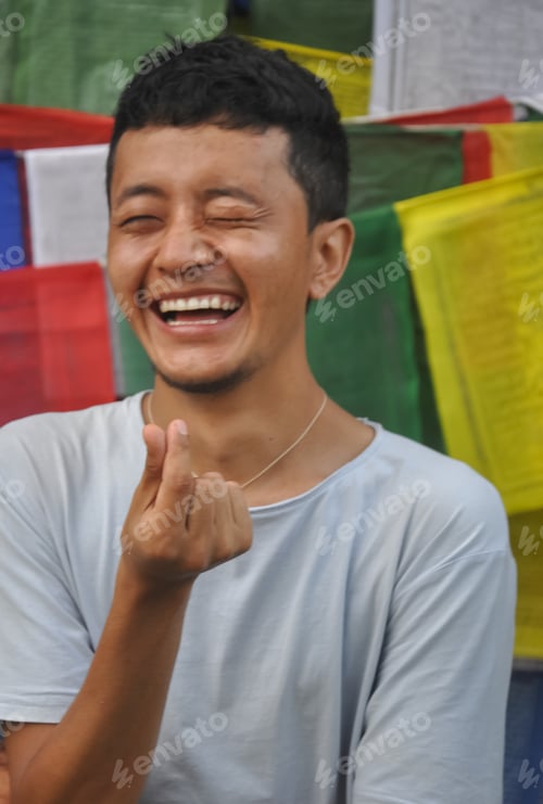 Preview: Closeup shot of a cheerful Tibetan guy making Korean love sign with his hand with looking sideways