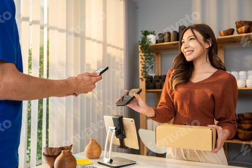 Preview: Attractive male customer using mobile phone paying for goods package.