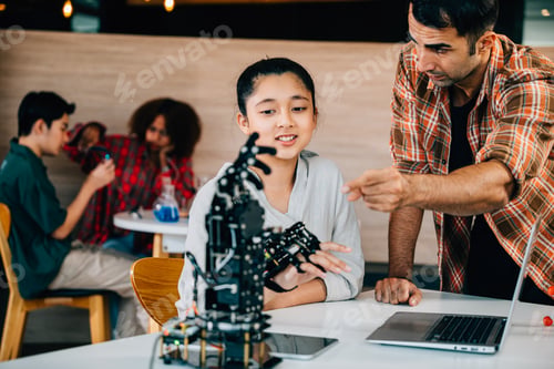 Preview: In classroom teacher aids student in building robotic arm for design and technology lesson