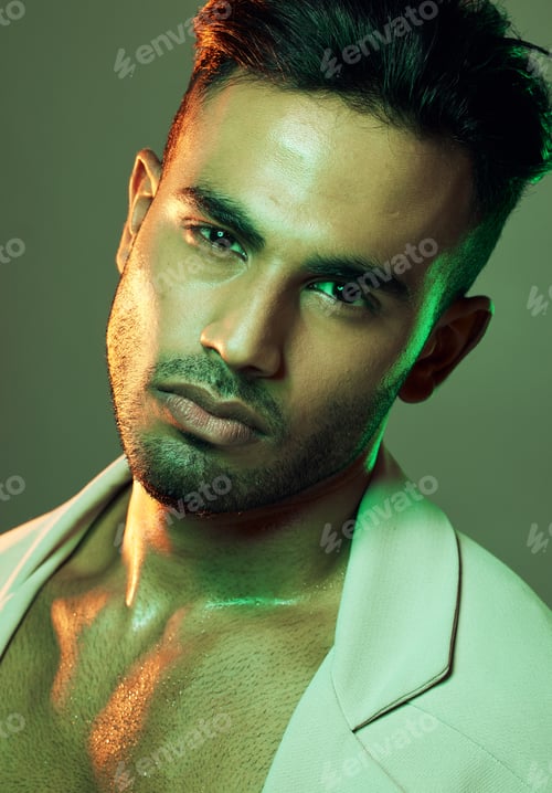 Preview: Fashion, green lights and portrait of sexy man from India in studio background creative shoot. Beau