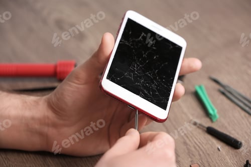 Preview: Technician fixing mobile phone at table, closeup. Device repair service