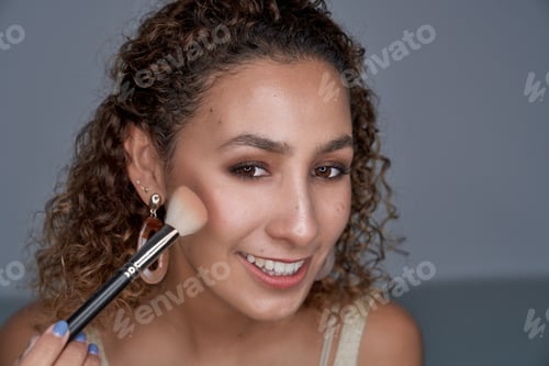 Preview: Smiling woman shading blush on cheek with professional brush