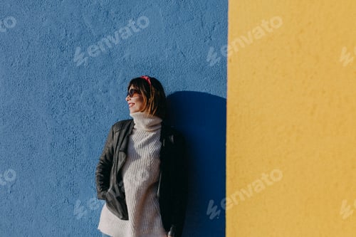 Preview: portrait of a young beautiful woman outdoors over blue and yellow background. Lifestyle