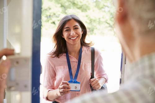 Preview: Senior man opening front door to young woman showing ID card