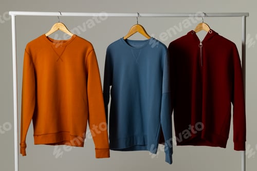 Preview: Coloured sweatshirts displayed on clothing rail and copy space on white background