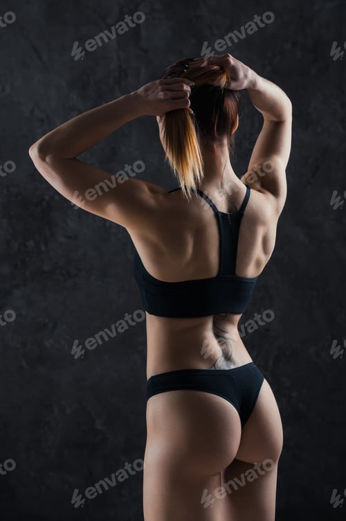 Preview: Young fitness girl getting prepared for the workout isolated on dark background