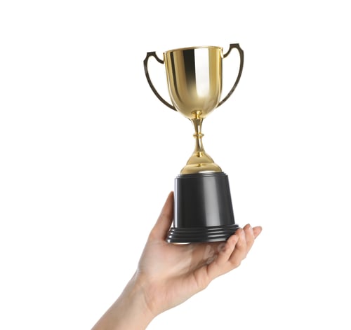Preview: Woman holding gold trophy cup on white background, closeup