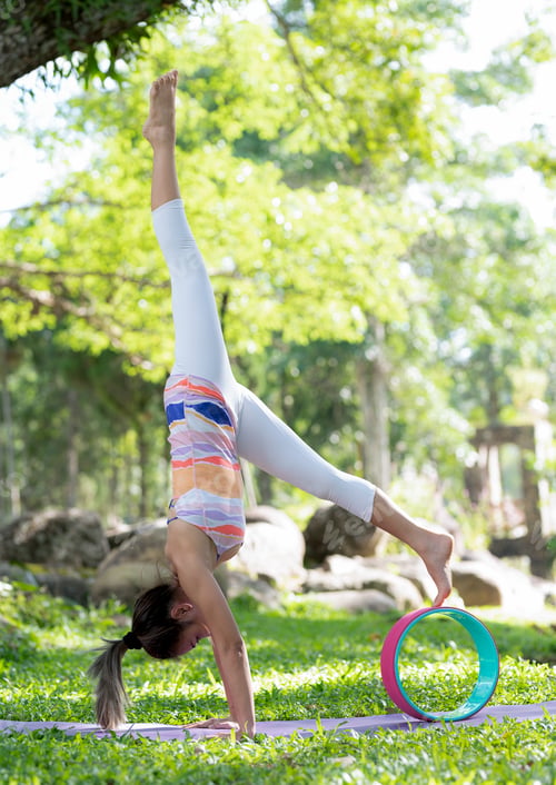 Preview: Young woman doing yoga exercises on the outdoor lawn.