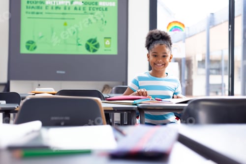 Preview: girl student sitting at classroom desk, viewing recycling slide, using colored pencils