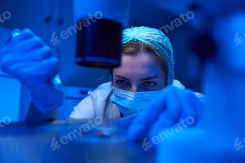 Preview: Woman in protective mask works with biomaterial in sterile laboratory