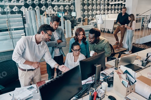 Preview: Group of young modern people in smart casual wear discussing business while working in the office