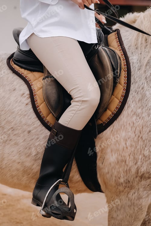 Preview: Close-up of a rider's legs in stirrups. A woman on a horse