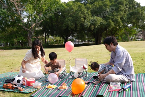 Preview: Asian family sitting in park with toys and parents and children.