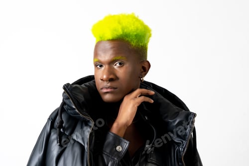 Preview: Black ethnic man in studio with white background, LGTBI concept, looking at camera with black jacket