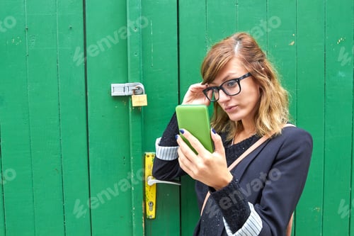 Preview: Cute Young Caucasian Woman Holding Modern Smartphone On The Street.