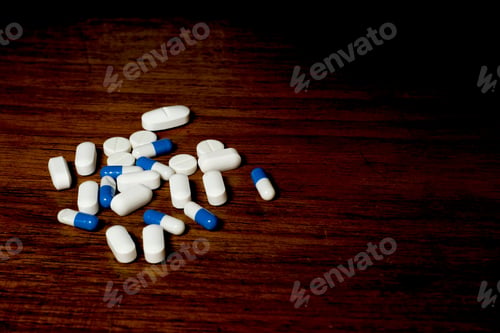 Preview: Pile of white and blue pills on a brown background
