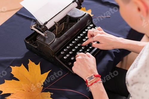 Preview: Hands of young woman, office worker, are typing text (letter) on old retro typewriter.