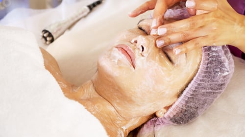 Preview: Cosmetologist applies a moisturizing mask on female face. Woman in a spa salon, cosmetic procedures