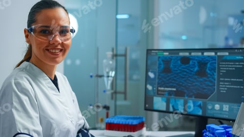 Preview: Portrait of a smiling chemist wearing safety glasses in lab looking at camera