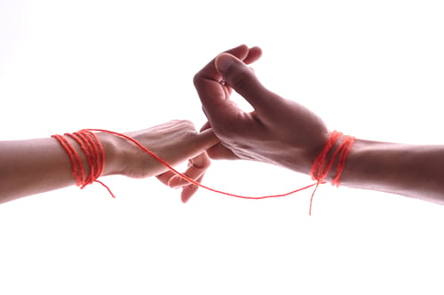 Preview: Male and female hands wrapped in red thread isolated on white, concept of desire and love