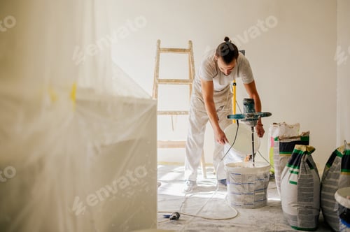 Preview: A laborer is adding water to a plaster mixture while renovating home.