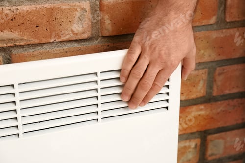 Preview: Man checking temperature of heating convector on brick, closeup