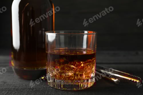 Preview: Bottle and glass of whiskey on wooden background, space for text