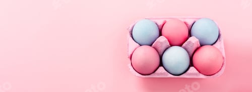 Preview: High angle view of colorful easter eggs in egg tray on pink background, panoramic shot