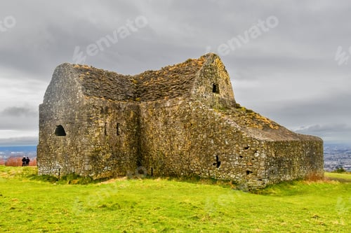 Preview: Traditional stone building situated atop a lush green meadow, with a gloomy sky in the background