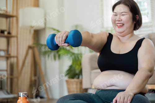Preview: Happy Overweight Woman Exercising at Home with Dumbbells for a Healthy Lifestyle and Fitness Routine