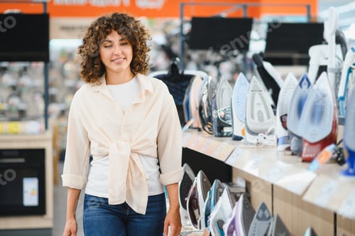 Vista previa: Woman choosing clothes iron in electronics store