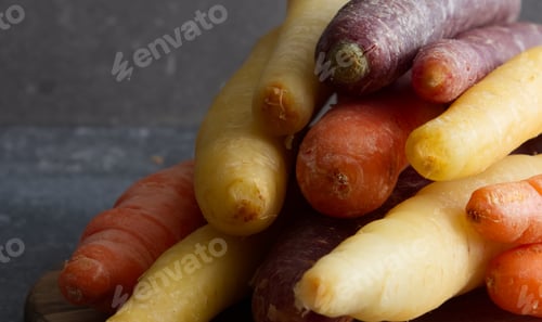 Preview: Rainbow carrots on a wooden stand close-up, yellow, purple, orange