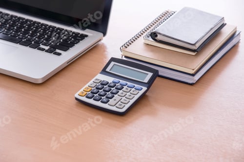 Preview: Wooden office desk table with laptop computer, glasses, notebook and calculator. flat lay.