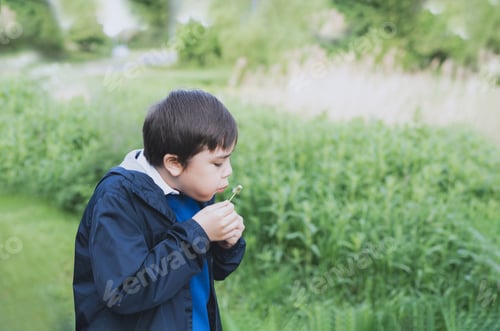 Preview: School kid blowing dandelion flower in spring park while walking to school in the morning.